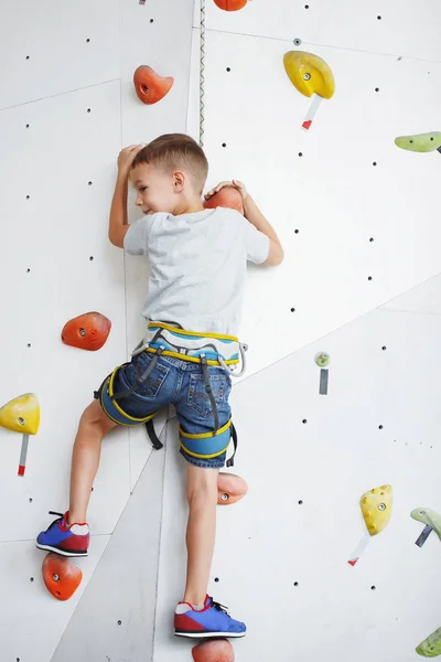 Cute little boy trains on the climbing wall indoor — Stock Photo, Image