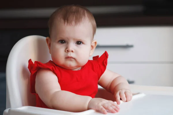 Egy piros ruha baba ül egy gyermek szék — Stock Fotó