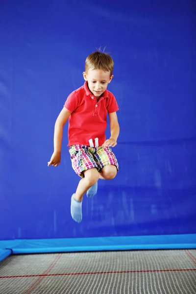 Kırmızı T-shirt ve şort fitness salonunda bir trambolin üzerinde içinde bir oğlan