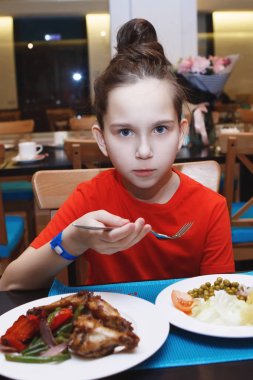 Sebze yeme bir restoranda bir masada kırmızı bir tişört, sevimli küçük bir kız