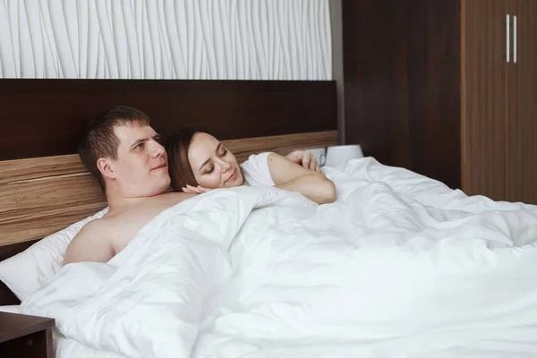 Młody piękny mąż i Żona, odpoczynek w łóżku pod biały koc w pokoju hotelowym — Zdjęcie stockowe