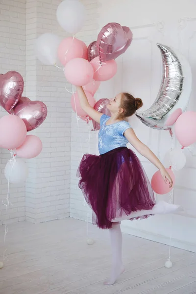 Nuori ballerina sinisissä vaatteissa ja violetti hame vaaleanpunaisilla ilmapalloilla ja hopeinen puolikuu valkoisella taustalla . — kuvapankkivalokuva