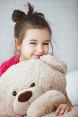 Uzun saçlı kız pembe tişört içinde bir oyuncak ayı ile hugs.