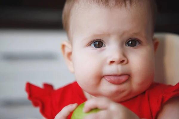 Bebé en un vestido rojo está sentado en la silla de un niño —  Fotos de Stock