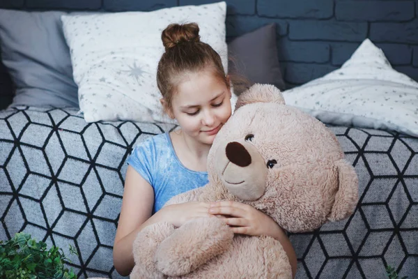 Uma jovem de roupas azuis em meia-mangueira branca senta-se com urso de brinquedo — Fotografia de Stock