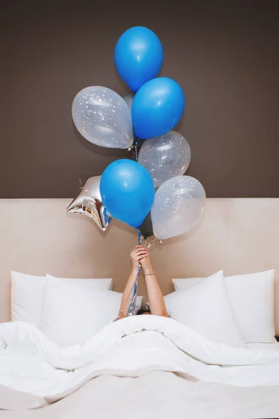 Νεαρή γυναίκα με μπαλόνια ξαπλώνει στο κρεβάτι. — Φωτογραφία Αρχείου