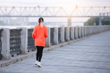 Nehrin kenarına doğru koşan bir kadın eğitim seansına katılmış. Arka plan.