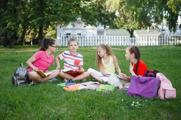Vier Kinderen Zitten Het Gazon Lezen Tekenen Het Stadspark — Stockfoto