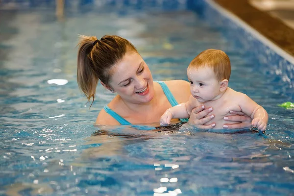 Woman child trainer and toddler swim and study in blue water pool