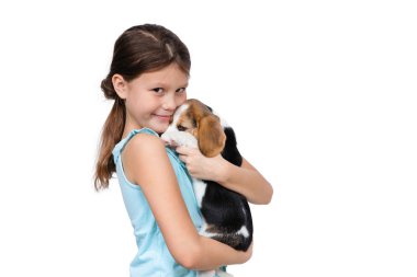 Genç kız elinde, beyaz bir arka planda, beyaz bir Beagle köpek cinsinin safkan bir yavrusunu tutuyor..