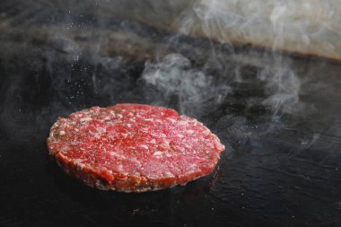 Doğranmış et pirzolası ve elektrikli ocakta dumanla kızartılıyor..