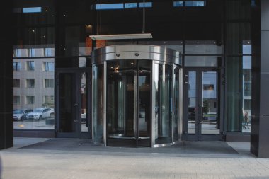 Ofis binasının ya da otelin girişi cam ve çelikten yapılmıştır. Gökyüzünün yansıması ve döner bir kapısı vardır..