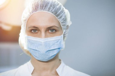Klinikte başlık ve maske takan cerrahi hemşire. Yakın plan portre. Sağlık, ameliyat..