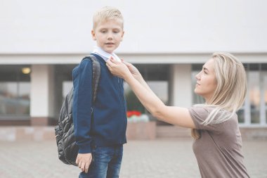 Anne oğlunun giyinmesine ve okula kadar ona eşlik etmesine yardım eder..