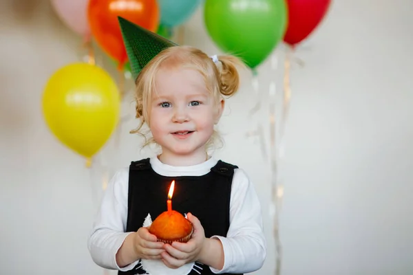 キャップの女の子はケーキの上に誕生日のろうそくを吹きます — ストック写真