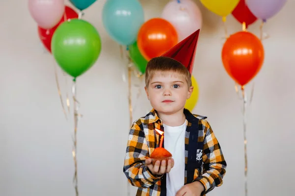 キャップの少年はケーキの上に誕生日のろうそくを吹き消す — ストック写真