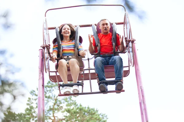 一个少女和一个男人在公园里玩着一个非常吸引人的荡秋千 感情爆炸 害怕坠落 高速休克 — 图库照片