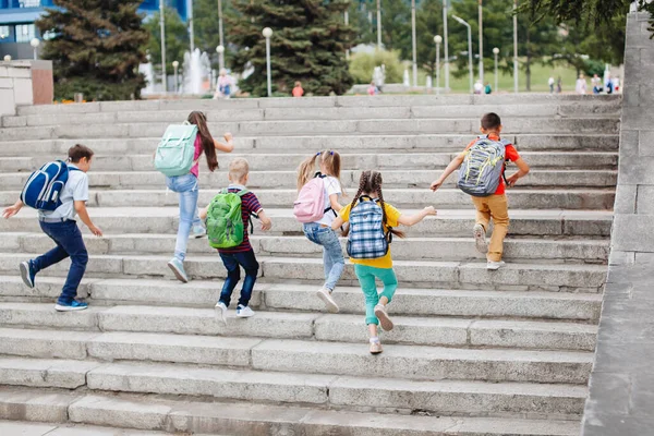 バックパック付きのカラフルな服の子供たちは学校までの階段を歩いています — ストック写真