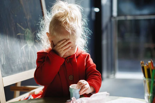 小さな女の子ブロンドとともに彼女の顔で彼女の手のひら — ストック写真