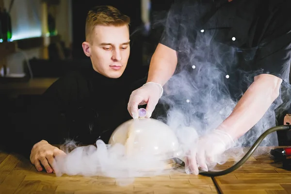 Waiter serves dishes with smoke for a client in a restaurant.