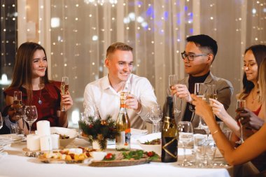 Noel kutlaması. Birkaç Asyalı ve Kafkasyalı tatil masasında. Seçilmiş, yumuşak odaklı. Eski filmin klasik etkisi. Gürültü ve tahıl için filtre.