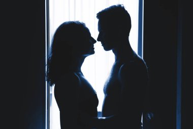 Siluet İki aşık adam ve kadın sarılıyor.