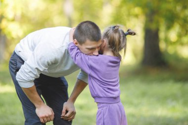 Baba ve kızı yaz parkında eğleniyor. Kız babasına sarılıyor..