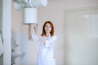 Kadın radyoloji uzmanı, tıbbi muayenehanede röntgen için ekipman hazırlıyor..