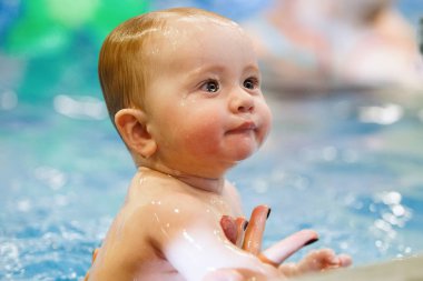 Mavi suyu olan bir havuzda sevimli, sevimli bir bebek. Yüzme eğitimi, sağlıklı yaşam tarzı..