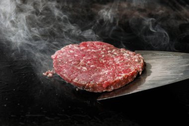 Doğranmış et pirzolası ve elektrikli ocakta dumanla kızartılıyor..