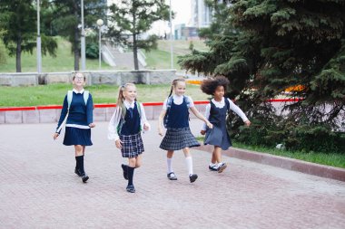 Üniformalı ve sırt çantalı öğrenciler okula gider..