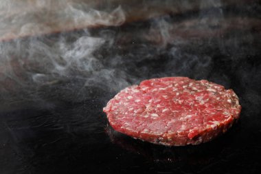 Doğranmış et pirzolası ve elektrikli ocakta dumanla kızartılıyor..