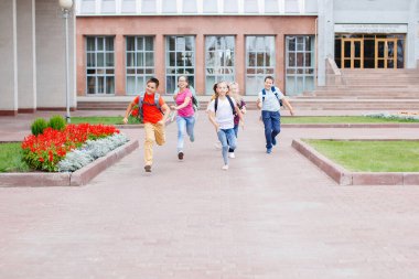 Sırt çantalı bir grup okul çocuğu dersten sonra okuldan kaçıyor..