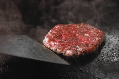 Doğranmış et pirzolası ve elektrikli ocakta dumanla kızartılıyor..