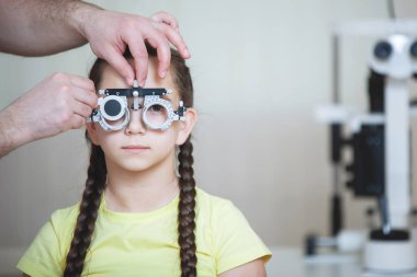 Örgülü sarı tişörtlü genç bir kız için Göz muayenesi.