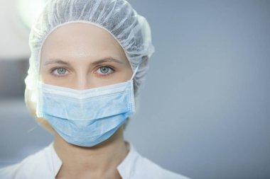 Klinikte başlık ve maske takan cerrahi hemşire. Yakın plan portre. Sağlık, ameliyat..