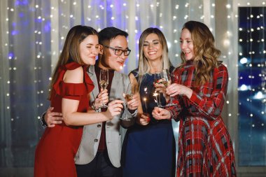 Bir grup insan ellerinde şampanya bardakları ve maytap ile şapkalar içinde tatilde gülüyor. Seçilmiş, yumuşak odaklı. Eski filmin klasik etkisi. Gürültü ve tahıl için filtre.