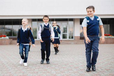 Bir grup okul çocuğu neşeli ve neşeli bir şekilde okuldan kaçıyor..