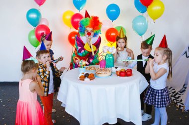 Çocuklar doğum günü partisinde bir palyaçoyla oynar ve eğlenir..