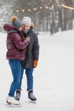 Aşıklar kışın buz pateni pistinde akıllı telefona bakar..