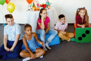 Çokuluslu çocuklar bir doğum günü kutlamasında toplar, şapkalar, şekerler dikkatle performansa bakın..