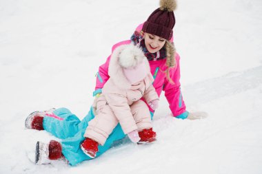 Anne ve kızı kışın açık havada karlı bir parkta..