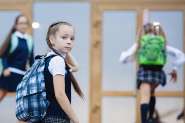 Üniformalı ve sırt çantalı öğrenciler okula gider..