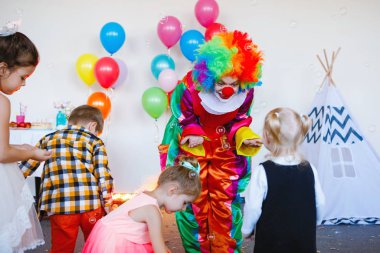 Çocuklar doğum günü partisinde bir palyaçoyla oynar ve eğlenir..