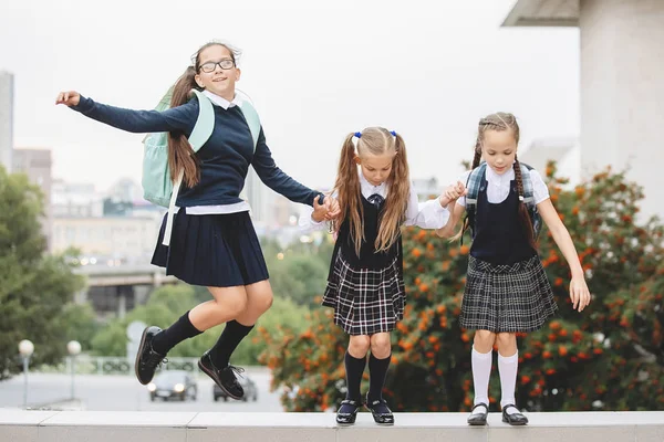 三个穿制服的女学生跳起来笑了 — 图库照片