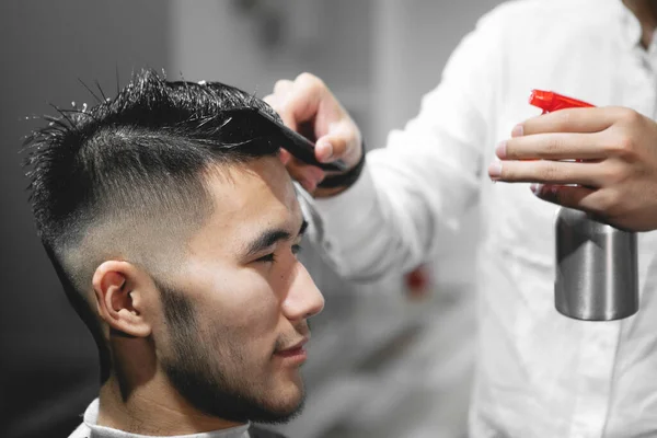 在美容院里 年轻的理发师在男人头上喷了些乳液 — 图库照片