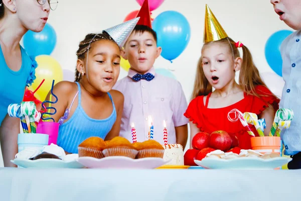 Children on a birthday celebration with balls, caps, sweets and laughs.