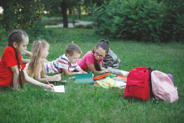 Cuatro Niños Están Tumbados Césped Del Parque Ciudad Leen Libros — Foto de Stock