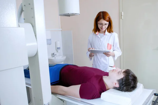 Female doctor radiologist prepares a patient for the procedure in a medical office.