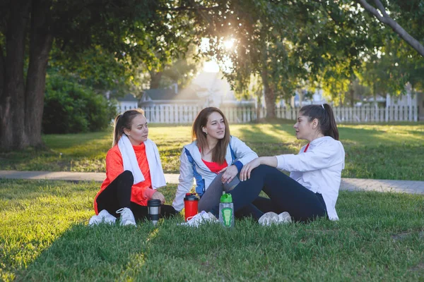 Trzy Kobiety Odzieży Sportowej Odpoczywają Latem Zielonym Trawniku Parku Miejskim — Zdjęcie stockowe
